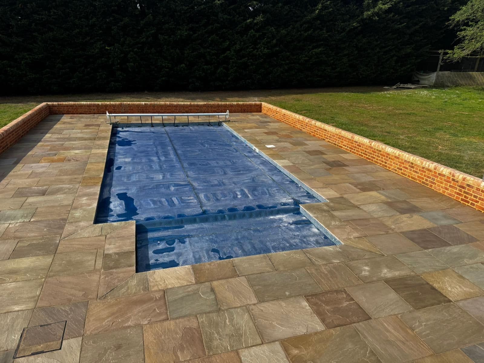 Sandstone pool terrace with brick edging, built by Coyne Landscapes