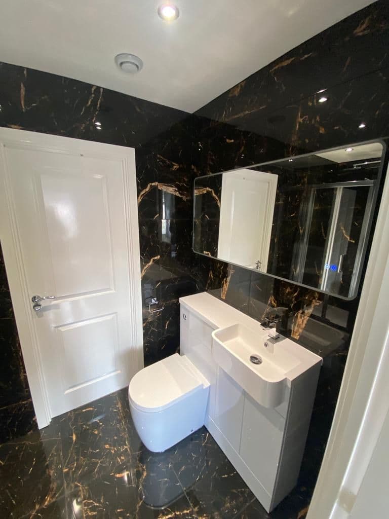 Cloakroom in black marble-effect tiles with a white vanity
