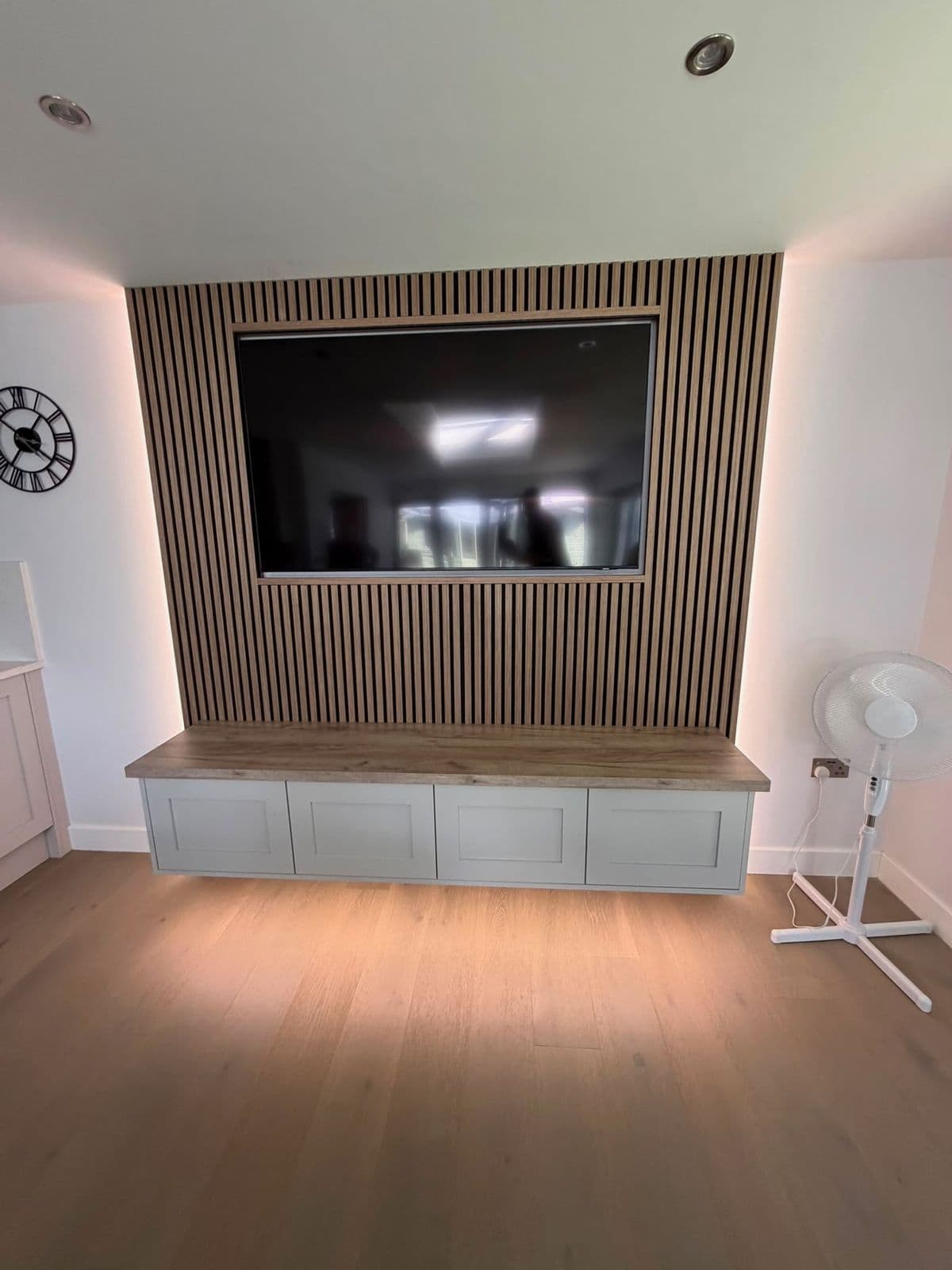 Media wall with oak slat panelling and built-in cabinetry
