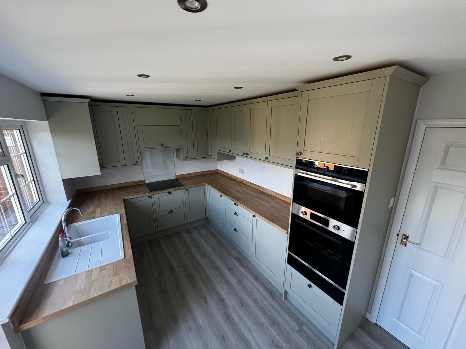 Sage shaker kitchen with oak worktops and a built-in double oven